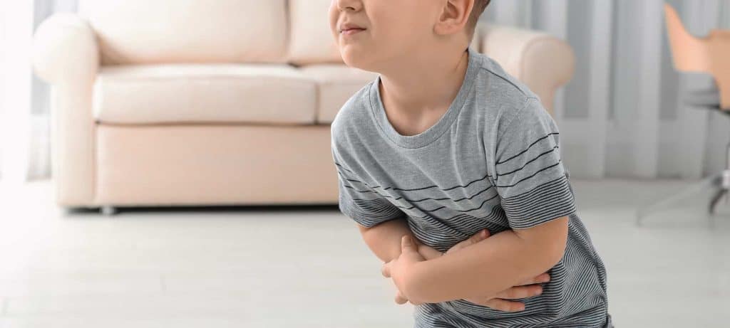 young boy holds sore stomach due to constipation