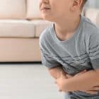 young boy holds sore stomach due to constipation